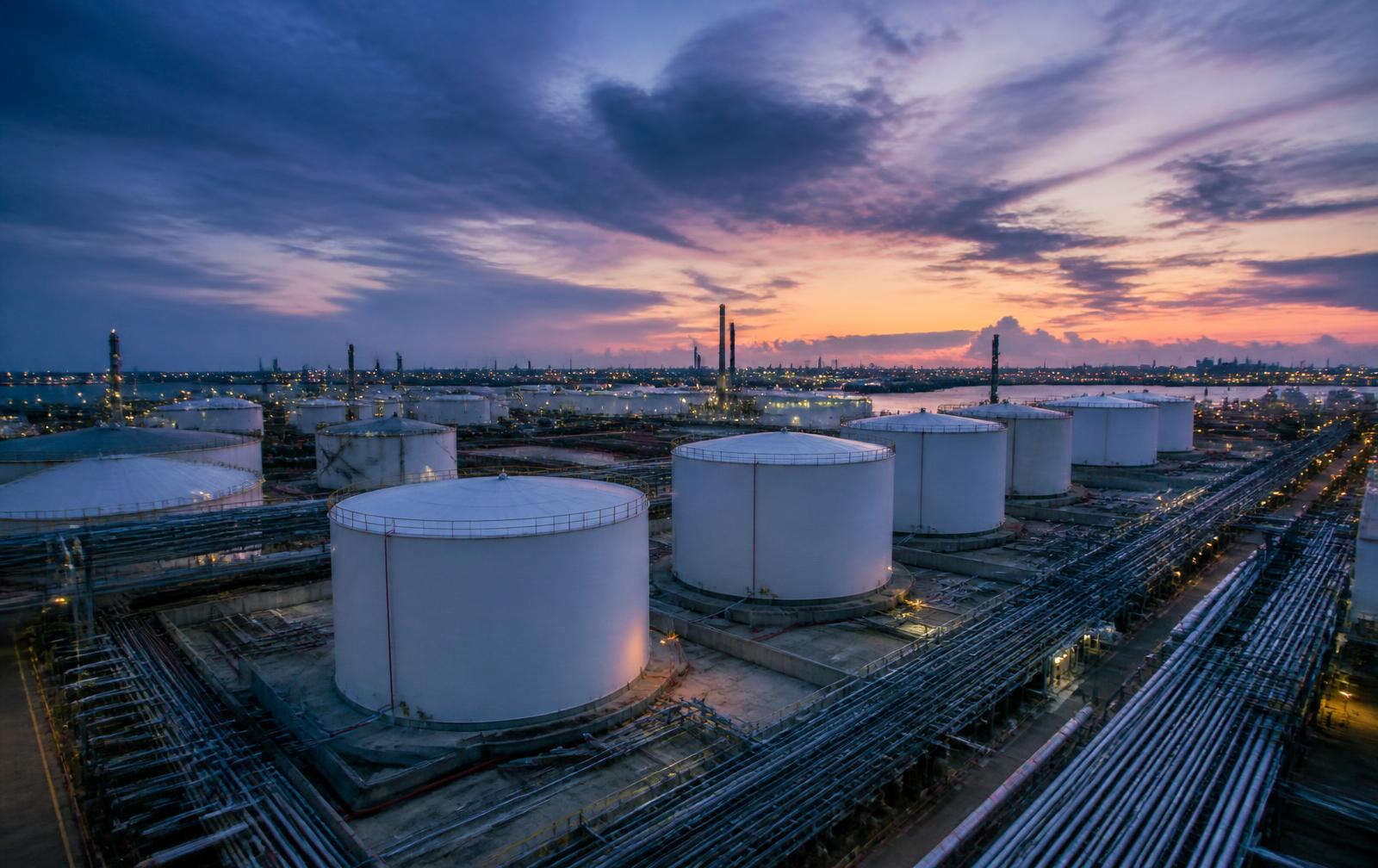 Industrial tank storage terminal and pipe racks in a European petrochemical port cluster at dusk